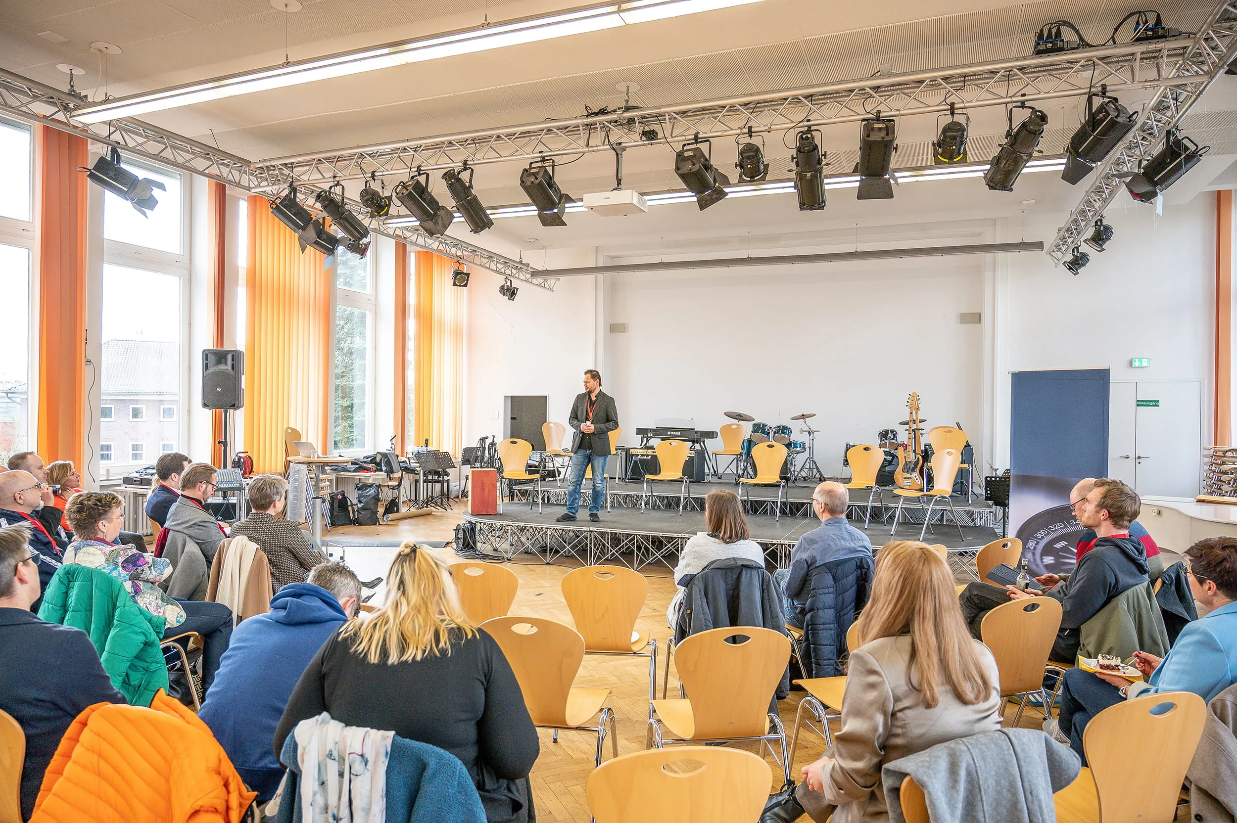 Ein Vortrag in einem großen Saal, das Publikum sitzt in Stuhlreihen