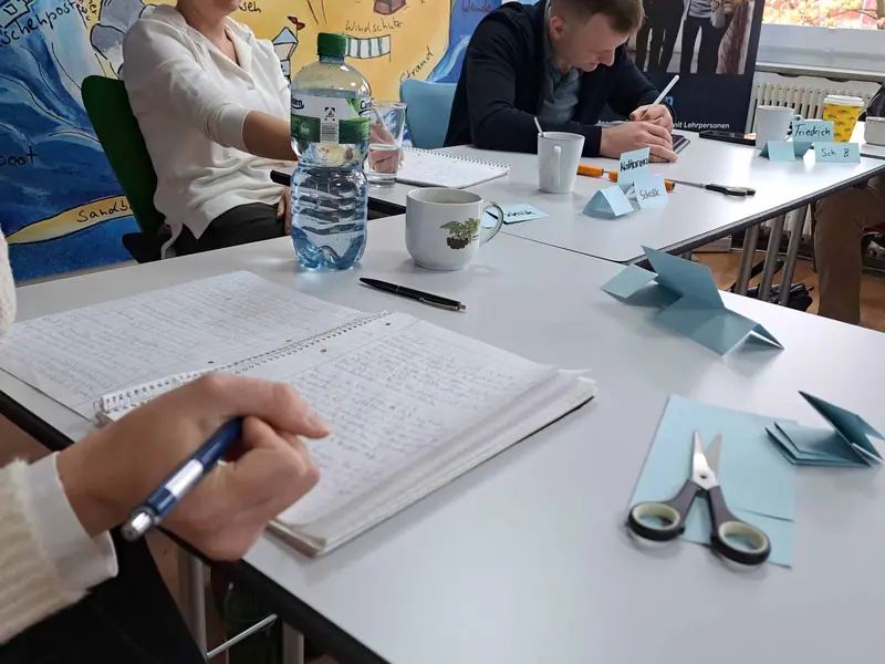 Teilnehmende arbeiten an Gruppentischen mit Notizen und Material